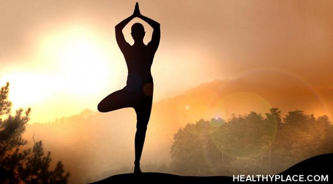 一个人做一个瑜伽姿势用一条腿和手臂伸展的头顶。背景是一个橙色的日出。